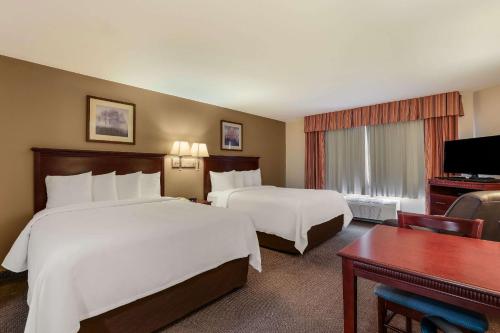 a hotel room with two beds and a desk at MainStay Suites Fitchburg - Madison in Madison