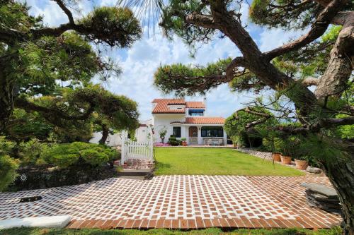une maison avec un jardin et une allée dans l'établissement Palm Tree Villa, à Seogwipo