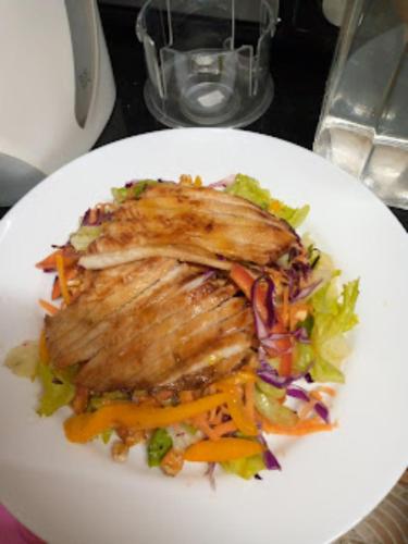 a white plate with a piece of meat and a salad at Melvic Hotel in Kisumu