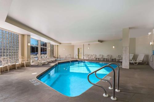 una piscina en una habitación de hotel con sillas alrededor en MainStay Suites Fitchburg - Madison, en Madison