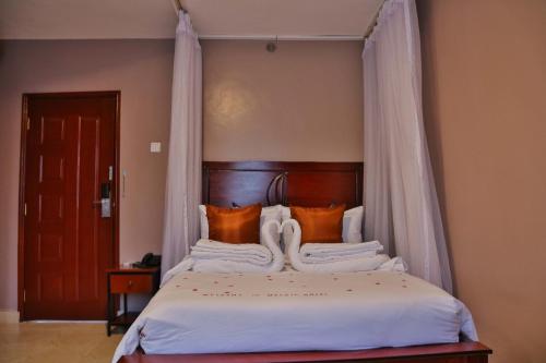 een slaapkamer met een hemelbed met oranje kussens bij Melvic Hotel in Kisumu