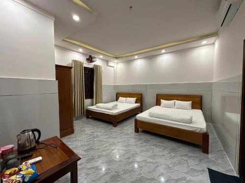 a bedroom with two beds and a desk and a table at Hoàng Linh Hotel in Buon Ma Thuot