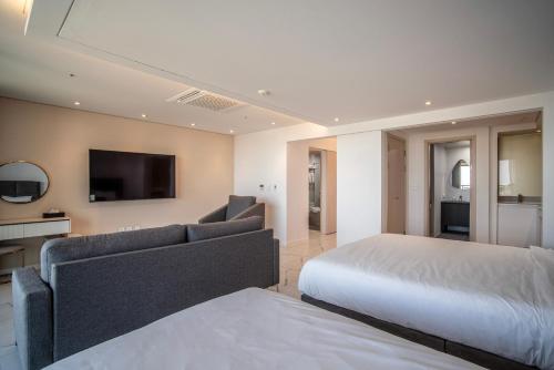 a bedroom with a bed and a couch and a tv at Villa de Aewol in Jeju