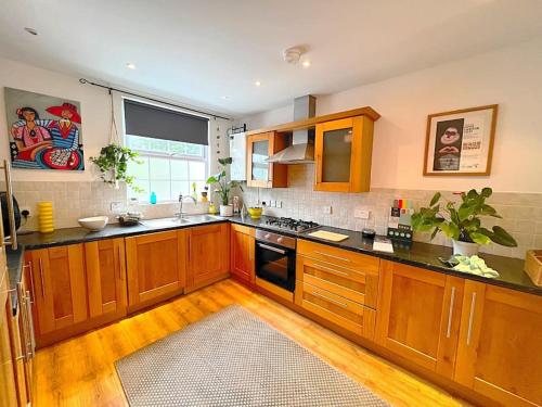a kitchen with wooden cabinets and black counter tops at True Colours Apartment in Central Location in Bangor
