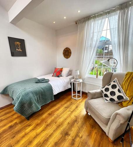 a bedroom with a bed and a couch and a window at True Colours Apartment in Central Location in Bangor