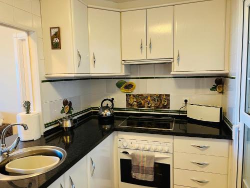 una cocina con armarios blancos y fregadero en Marina II apartment, en Huelva