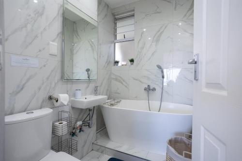 a white bathroom with a tub and a sink at 24 Sea Lodge - Sea Viewing Apartment in Durban
