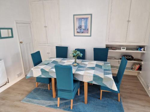 a dining room with a table and blue chairs at Bob's House quiet retreat in 3 bed house with gym in Loughborough