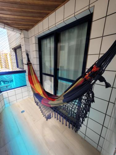 a hammock hanging on a wall next to a window at Apto inteligente com Alexa, Wi-fi e Smart TV. in Praia Grande