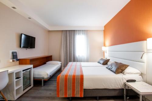 a hotel room with two beds and a tv at Catalonia Conde de Floridablanca in Murcia