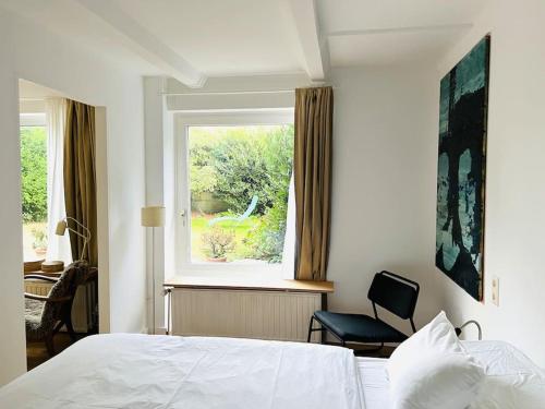 ein Schlafzimmer mit einem Bett, einem Fenster und einem Stuhl in der Unterkunft Stylisches Haus mit Garten in zentraler Lage in Wuppertal