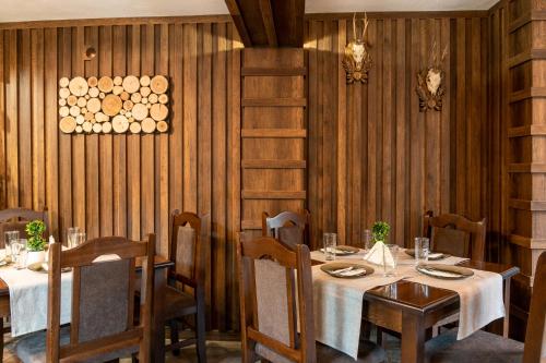 a dining room with tables and chairs and wooden walls at Beluga Guest House in Velingrad