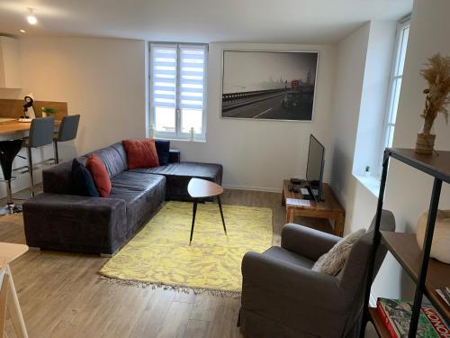 a living room with a couch and a table at Bel Appartement Climatisé au cœur du village in Saint-Aubin