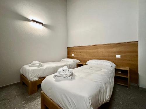 two beds in a room with white sheets at Case Verdi in Bardonecchia