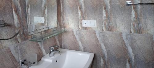 ein Bad mit einem Waschbecken und einem Wandspiegel in der Unterkunft Thuvaraga Inn in Nuwara Eliya