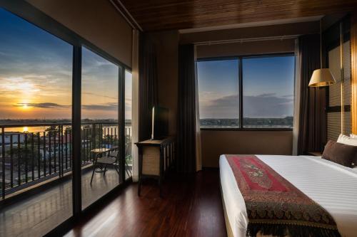 um quarto de hotel com uma cama e janelas grandes em Amanta Hotel Nongkhai em Nong Khai