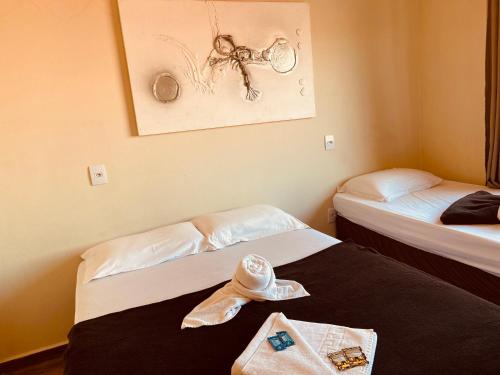 a room with two beds with a hat on the bed at Pousada Mar de Almirante in Penha