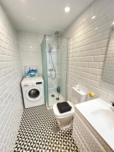 a bathroom with a shower toilet and a washing machine at Apartamento Oviedo Parque del Oeste in Oviedo