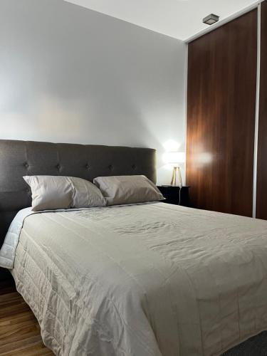 a bedroom with a large white bed with a brown headboard at Temporario La Plata2 in La Plata