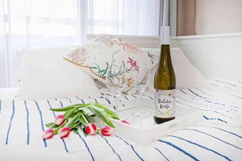 Una botella de vino y una copa y flores en la cama. en Silver Lodge Ezüstpart Apartman, en Siófok