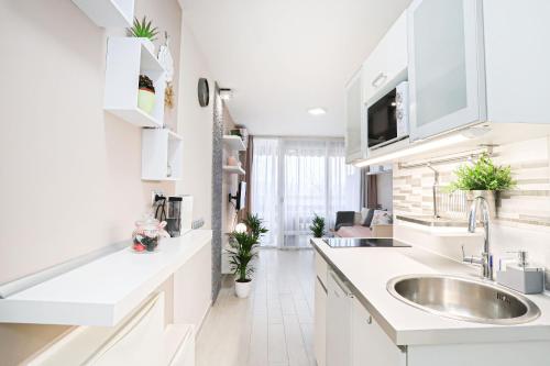 eine weiße Küche mit einer Spüle und einer Theke in der Unterkunft Silver Lodge Ezüstpart Apartman in Siófok