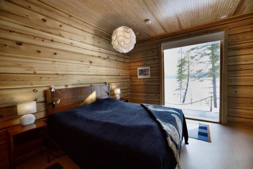 ein Schlafzimmer mit einem Bett in einer Holzhütte in der Unterkunft Villa Northern Lights by DG Lomailu, Lapland, Finland in Kyrö