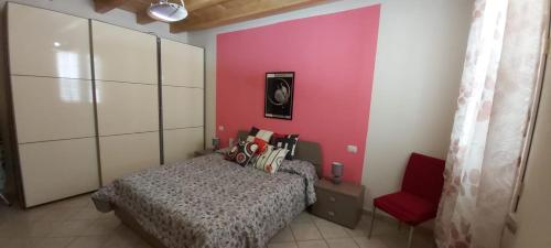 um quarto com uma cama e uma cadeira vermelha em SWEET HOME- AMPIO BIVANO A 10 MINUTI DALLE SPIAGGE em Quartu SantʼElena