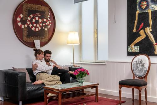 Dois homens sentados num sofá na sala de estar. em Art Boutique Hotel Chamarel em Denia