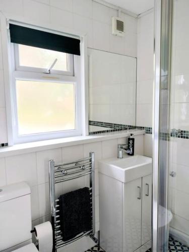 a white bathroom with a sink and a window at 271 Riverside, Glan Gwna Holiday Park in Caeathro