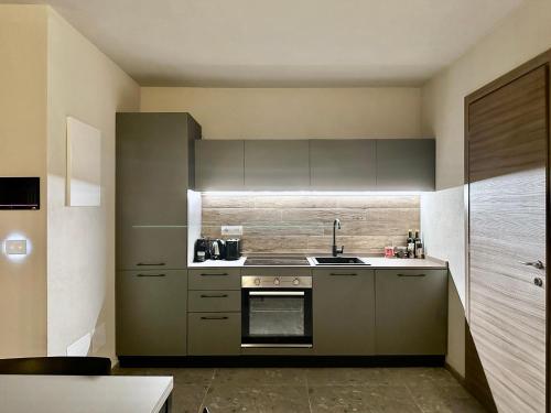 a kitchen with gray cabinets and a stove top oven at Case Verdi in Bardonecchia