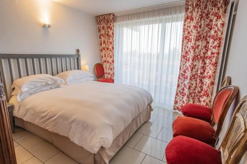 a bedroom with a bed and a window with red chairs at Appartement Mozart in Strasbourg