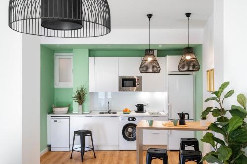 kuchnia z białymi szafkami oraz stołem i stołkami w obiekcie Lola 14 Suite Apartment w Sewilli