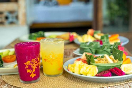 un tavolo con piatti di cibo e due bicchieri di succo di Tano Home Villas ad Ubud