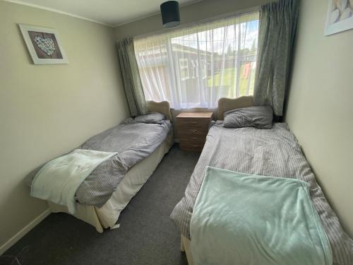 two beds in a room with a window at Sunee Holidays Chalet in Hemsby