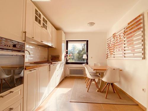 a kitchen with white cabinets and a table and chairs at Ferienwohnung Elisa in Tiefenbach