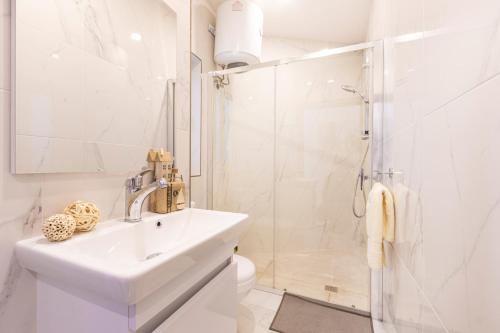 La salle de bains blanche est pourvue d'un lavabo et d'une douche. dans l'établissement H1- Modern & Spacious 3 Bedroom Apartment, à San Ġwann