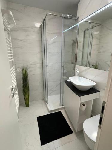 La salle de bains blanche est pourvue d'un lavabo et d'une douche. dans l'établissement Studio Pod Kaninom, à Bovec