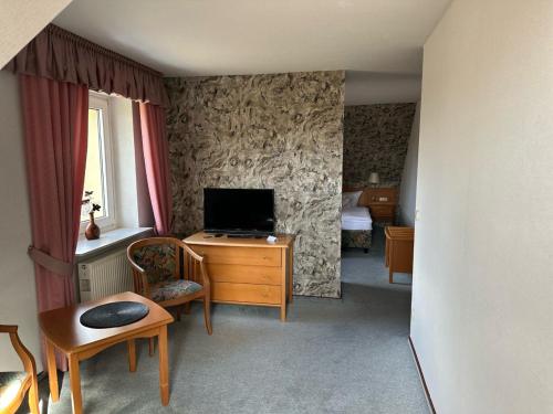 a room with a television and a desk with a chair at Gasthaus AFINA in Süsel