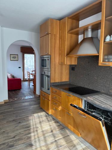 a kitchen with wooden cabinets and a living room at Casa Berlanda in Fiera di Primiero