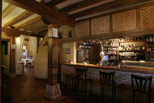 a bar in a restaurant with wooden ceilings and bar stools at Posada el Zaguan in Turégano