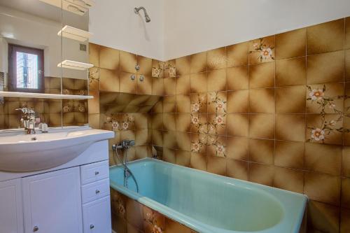 La salle de bains est pourvue d'une baignoire bleue et d'un lavabo. dans l'établissement Appartement Lei Jas, à Sainte-Maxime