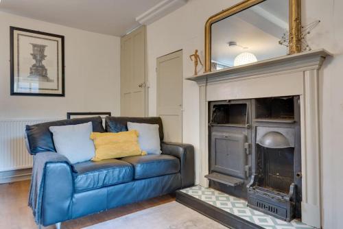 a living room with a blue couch and a fireplace at Music School Cottage 1 in Oundle