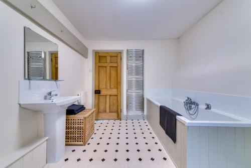 a bathroom with a tub and a sink and a mirror at Music School Cottage 1 in Oundle