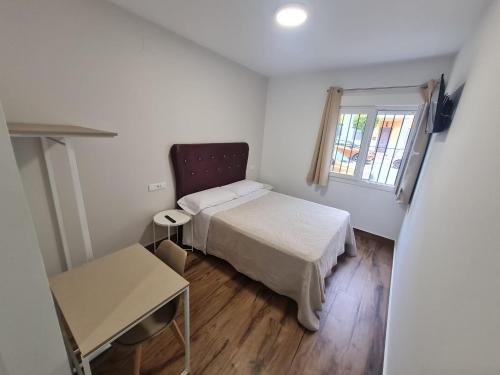 um pequeno quarto com uma cama e uma janela em Hostal Santa Ana em Huelva
