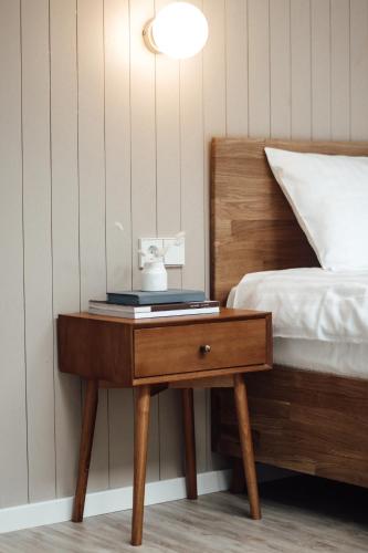 a nightstand with a clock on it next to a bed at Poilsio nameliai - B E L A I K O in Kretinga