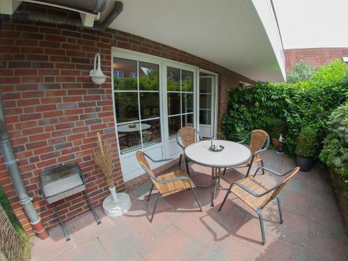 a patio with a table and chairs and a brick wall at Ferienwohnung Die Muschel, FeWo Vermittlung Nordsee in Dangast