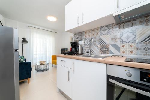 a kitchen with white cabinets and a sink at Danai & Palm Residential Complexes in Ofrínion