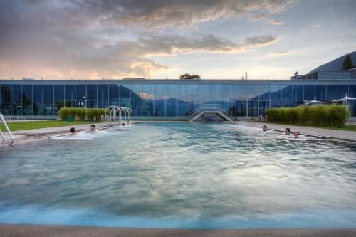 a pool in front of a building with people in it at Apart Holidays - Residenza Flora in Locarno