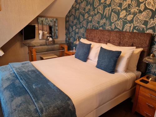 a bedroom with a large bed with blue pillows at Brookside Guest House & Mini Spa in Brixham