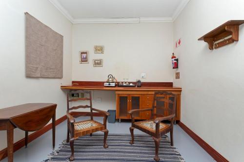 a room with a wooden desk and two chairs at Teak Place Guest Rooms in Krugersdorp